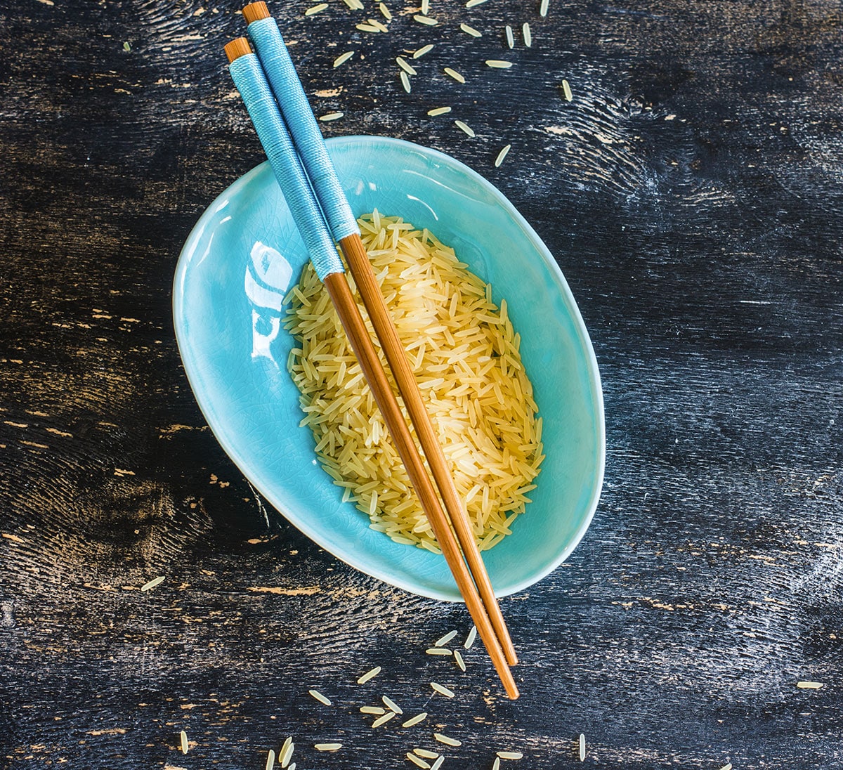 A bowl of rice and chopsticks on a wooden table.