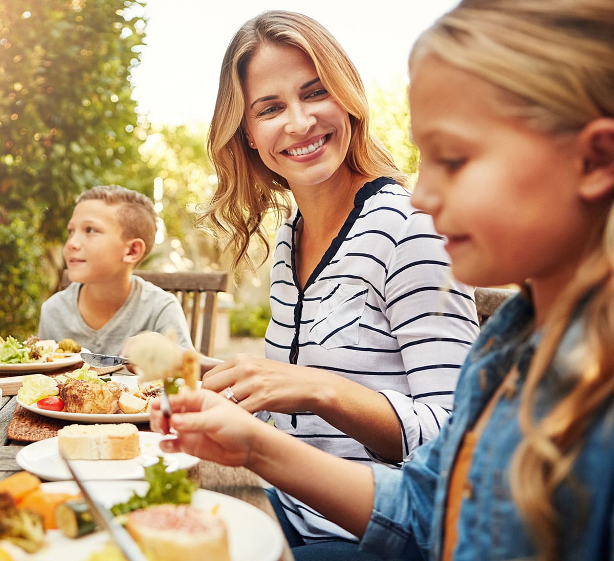 A woman and her children enjoying a meal outdoors.